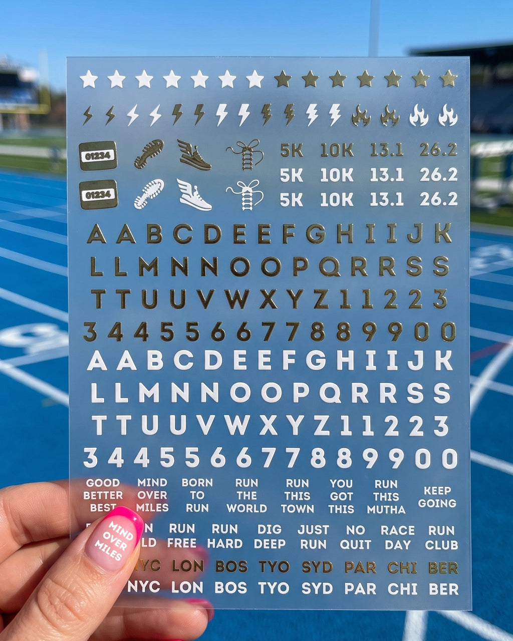 Hand holding the running nail sticker sheet over a blue track